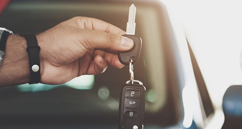 A person's hand holding a car key and remote fob