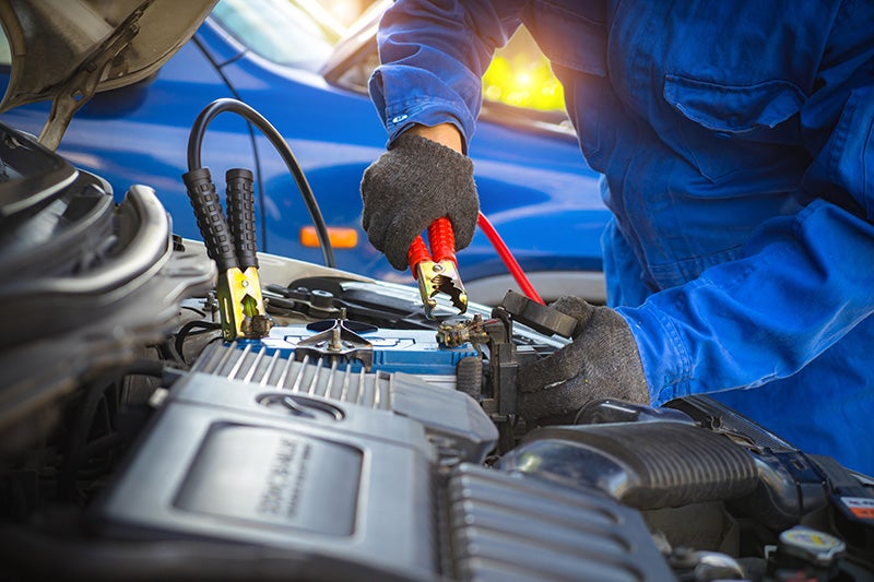 Mechanic using jumper cables on car battery